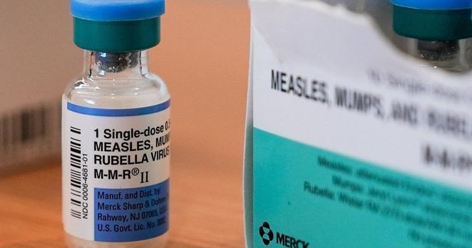 Ein medizinisches Glasfläschen, das eine klare Flüssigkeit enthält mit der Beschriftung „eine Dosis MMR-Impfung“