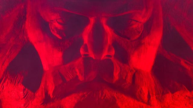 Eine Nahaufnahme des mit rotem Licht angestrahlten Karl-Marx-Monuments in Chemnitz