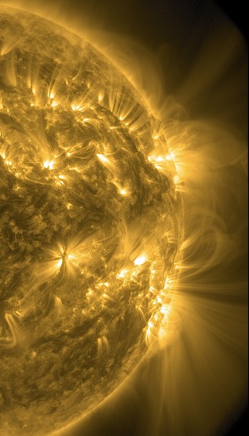 Die rechte Hälfte der erdzugewandten Seite der Sonne in gelber Farbe. Unzählige kleinere und größere heller dargestellte Bereiche, aus denen Strahlen in die Umgebung schießen. Am Rand breitet sich Strahlung wie ein Fächer weit ins All aus.