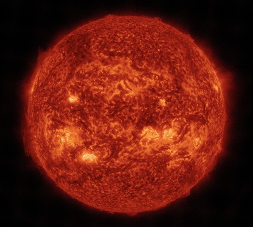 Die Sonne im aktuellen Bild des Satelliten SDO und diesmal in orangeroter Farbe mit einigen Aktiven Regionen, die heller dargestellt sind. Sie sehen her gelb aus, als ob die Sonne von innen glühen würde. Drumherum das Schwarz des Alls.