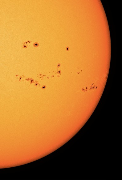 Der Bereich rechts unten auf der erdzugewandten Seite der Sonne in gelber bis orangefarbener Darstellung. Enorm viele Sonnenflecken - sicher ein Dutzend - sind hier als dunkle Punkte wiedergegeben. 