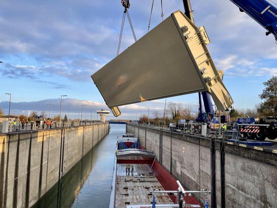An einem Kran schwebt das neue Tor in seine Position.
