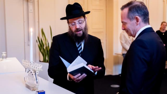 Yehuda Teichtal hält den Talmud, aus dem er vorliest. Neben ihm steht Volker Wissing.
