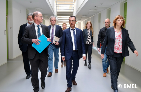 Cem Özdemir und BVL Präsident Friedel Cramer laufen mit anderen Personen einen Flur entlang.